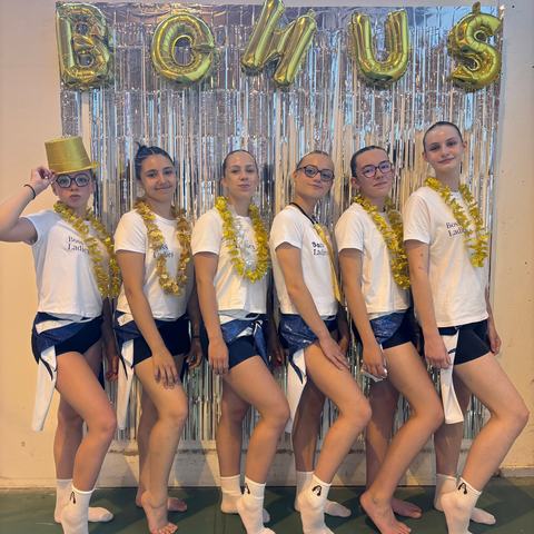 Les gymnastes en tenue de fête devant des ballons dorés