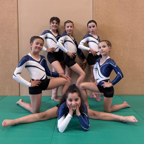 De jeunes gymnastes posent au sol, l'une en grand écart